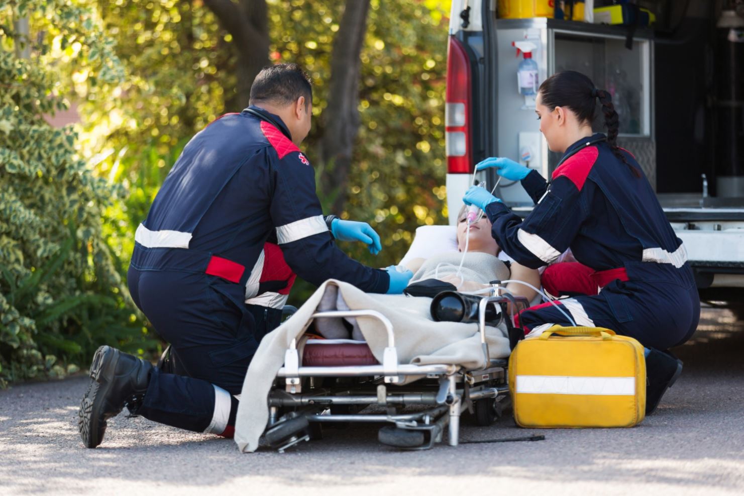 Ambulance workers fixing an IV to a boy in a stretcher.