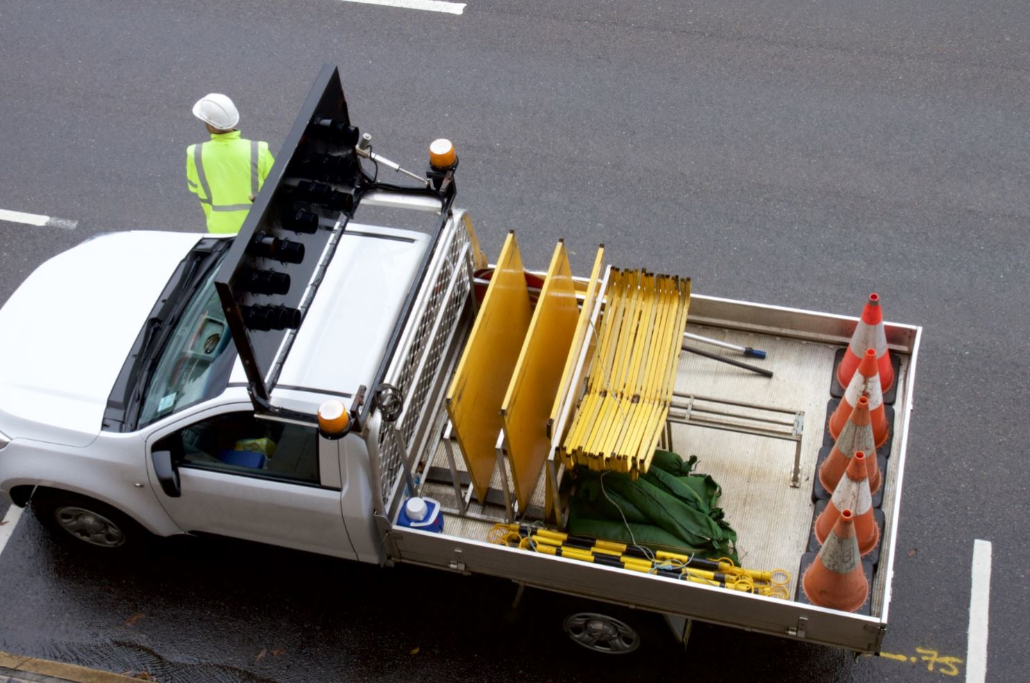 Arial view of a construction worker standing on the road next to the truck with traffic cones.