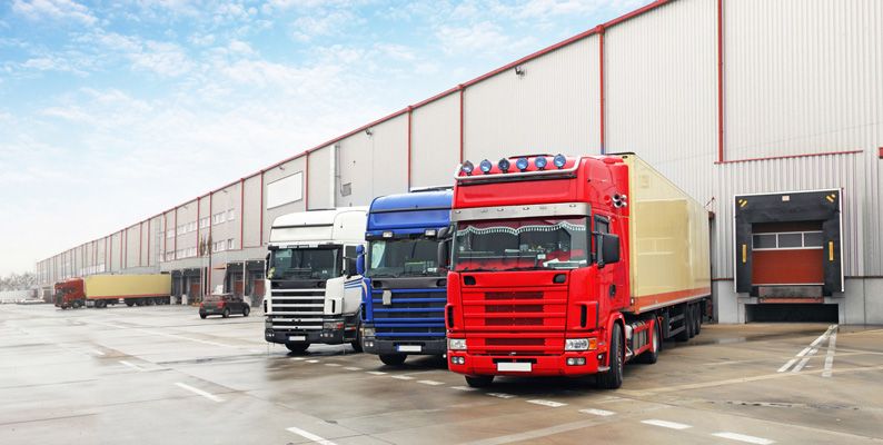 Trucks with IVMS tracking devices installed unloading at a warehouse.