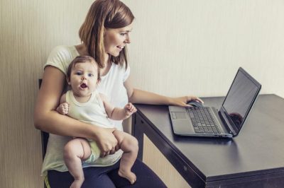 Mother working with child on lap.