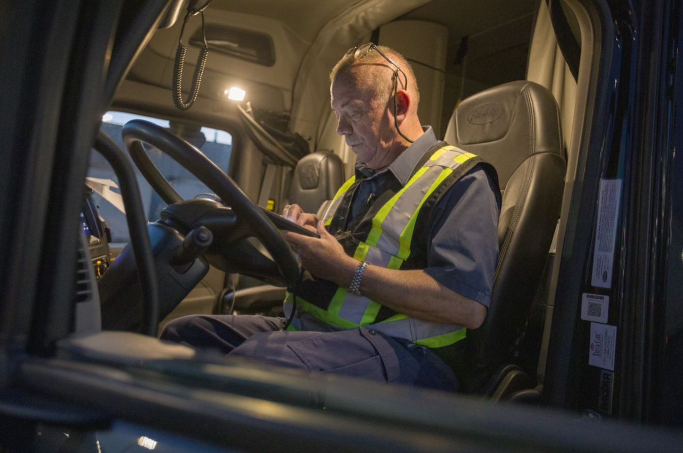 Truck driver looking at a mobile device inside truck cabin.